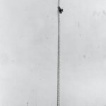 Black and white photo of a biplane stuck 300 feet up a 350 foot tall radio mast