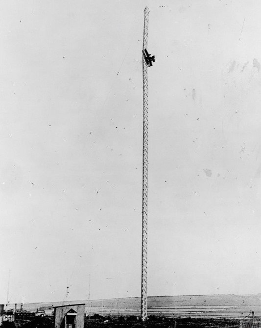 Black and white photo of a biplane stuck 300 feet up a 350 foot tall radio mast
