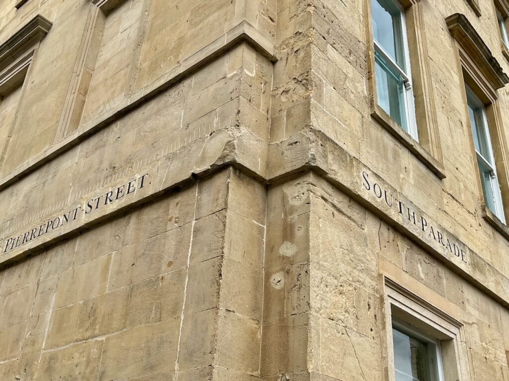 Corner view of a beige stone building with "PIERREPONT STREET" and "SOUTH PARADE" inscriptions.